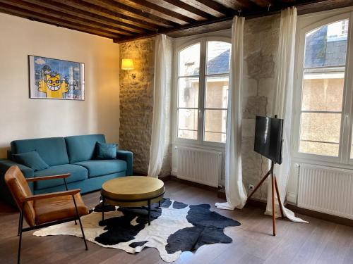 un salon avec un canapé bleu et une télévision dans l'établissement Le repaire d'Esmeralda, à Orléans