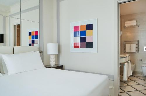 a white bedroom with a bed and a bathroom at UNAHOTELS Trastevere Roma in Rome