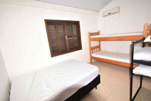 um quarto com 2 beliches e uma janela em Casa Canela, 450 mts da Praia de Mariscal. em Bombinhas