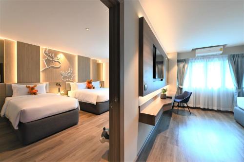 a hotel room with two beds and a couch at Moose Hotel Nimman in Chiang Mai