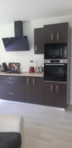 a kitchen with black cabinets and a microwave at Loarive in Saint-Gilles les Bains