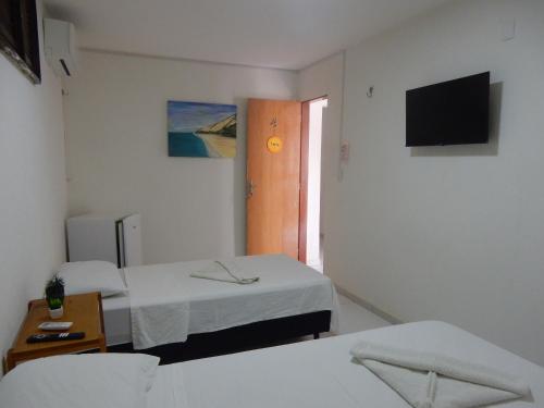 a room with two beds and a television on the wall at Pousada Ah Mar in Canoa Quebrada