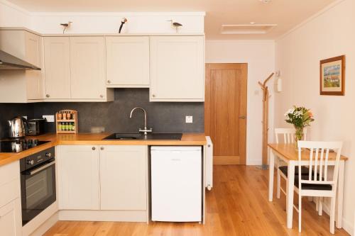 cocina con armarios blancos y mesa de madera en An Cala Beag Self Catering apartment on The Waternish Peninsula, en Hallin