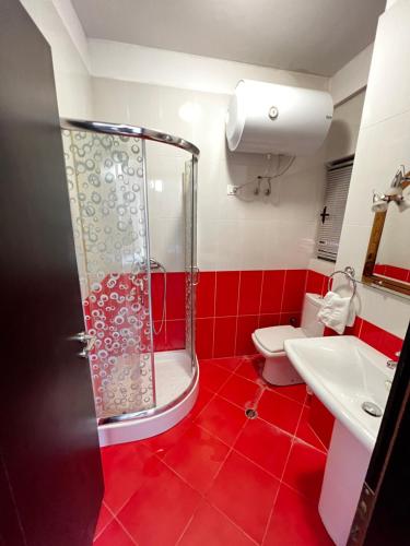 une salle de bain rouge avec douche et toilettes dans l'établissement Grande Veranda 2, à Tirana