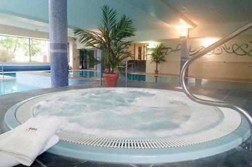 a hot tub in the middle of a room with a pool at Abbey Hotel Roscommon in Roscommon