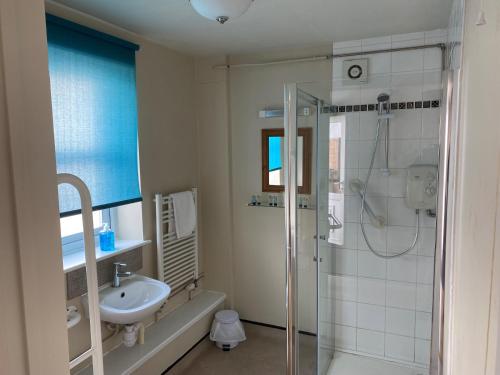 een badkamer met een glazen douche en een wastafel bij The Bullshead, Arthingworth House B&B in Market Harborough