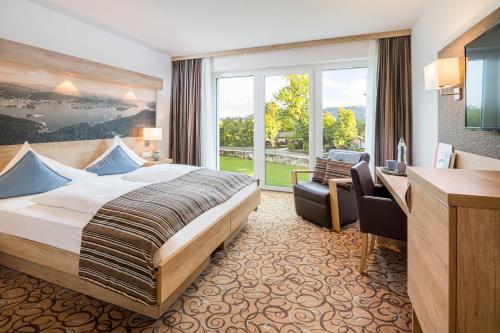 um quarto de hotel com uma cama e uma secretária em Seehotel Das JO em Pörtschach am Wörthersee