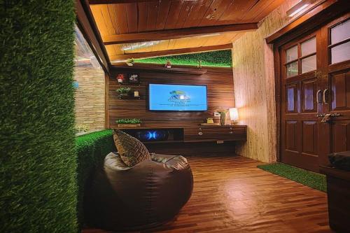 a living room with a couch and a tv in a room at Family Retreat - The Forest Dak Bangalow in Rāmgarh