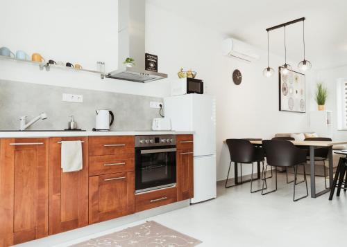 a kitchen with wooden cabinets and a table with chairs at Major11 apartman - Zsolnay negyed in Pécs