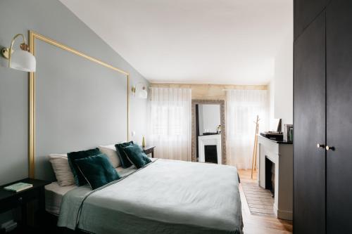 een slaapkamer met een groot wit bed met groene kussens bij Avenue Ferry in Libourne