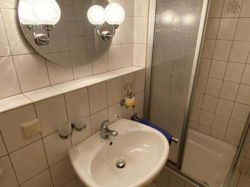 a bathroom with a sink and a mirror and a tub at Hotel Bielatal in Olbernhau