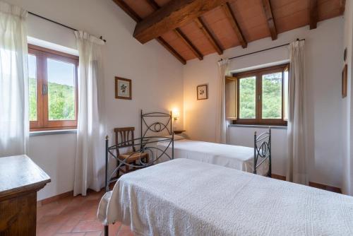 een slaapkamer met 2 bedden en 2 ramen bij Casale Falco Grande in Chiusi della Verna