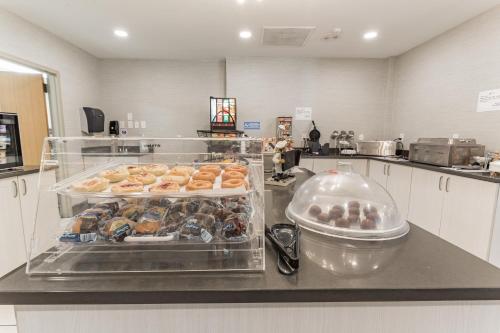 a kitchen with a counter with trays of donuts at Orangewood Inn & Suites Kansas City Airport in Kansas City