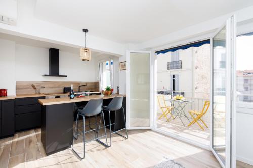 une cuisine avec des placards noirs et un comptoir avec des tabourets dans l'établissement Palladium 148 YourHostHelper, à Cannes