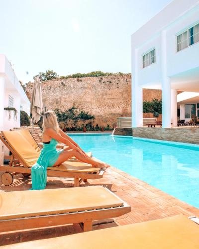 a woman sitting on a chair next to a swimming pool at Baluarte da Vila Apartments in Lagos