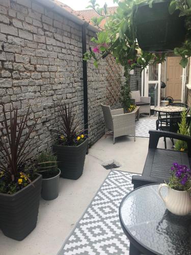 a patio with chairs and tables and potted plants at Large Cottage, Beach, Pubs Shops, Netflix, BBQ, Dog Friendly in Hunmanby