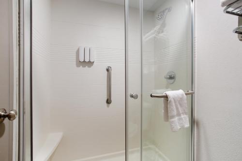 W łazience znajduje się prysznic ze szklanymi drzwiami. w obiekcie Orangewood Inn & Suites Kansas City Airport w mieście Kansas City