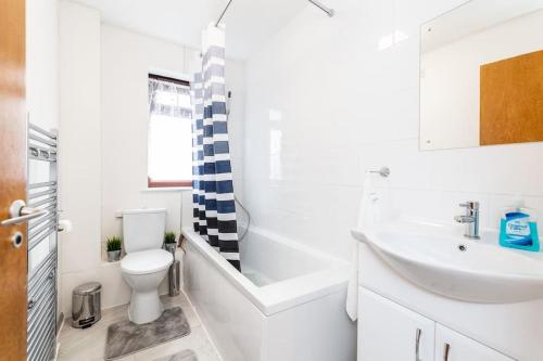 uma casa de banho branca com um lavatório e um WC em Cosy 2 bedroom house! Dagenham! Free parking em Goodmayes