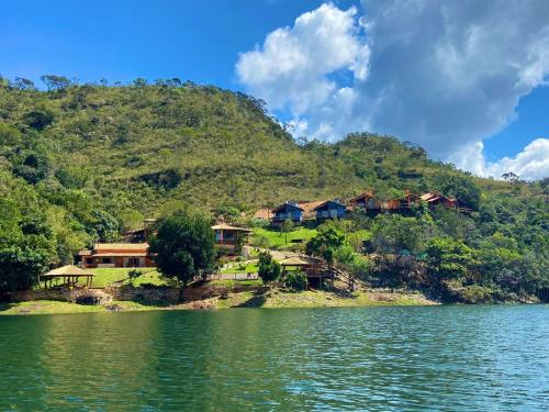 un grupo de casas en una colina junto a un cuerpo de agua en Pousada Fecho da Serra, en Capitólio
