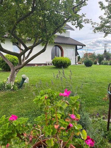 a white house with pink flowers in the yard at Kuća za odmor Sanja in Kupres