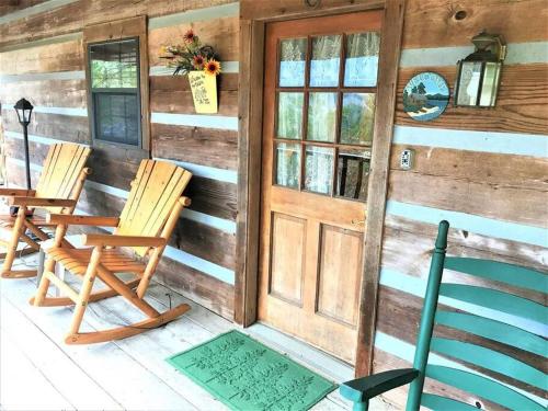 a porch of a cabin with two chairs and a door at R&R Retreat in Sunshine
