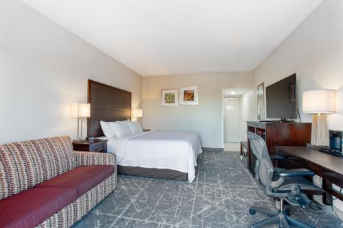 a hotel room with a bed and a desk at Orangewood Inn & Suites Kansas City Airport in Kansas City