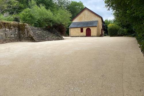 un petit bâtiment avec une porte rouge sur une route dans l'établissement Villa du Cerney - Lake des Settons, à Moux-en-Morvan