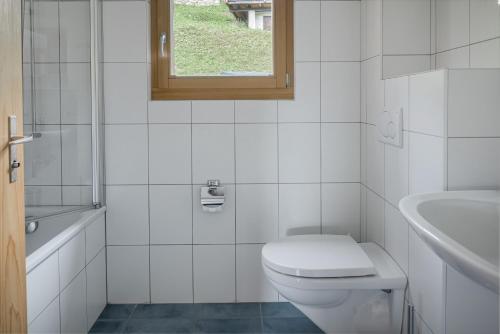 ein weißes Bad mit einem WC und einem Waschbecken in der Unterkunft Camelot 3 in Bettmeralp