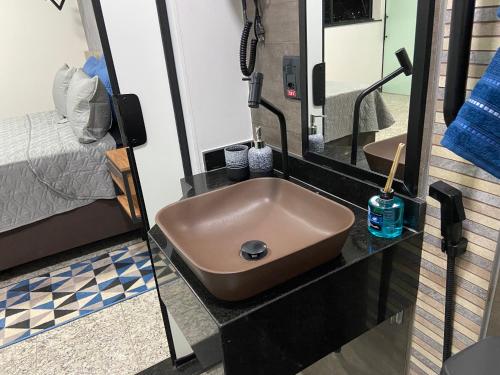 a bathroom with a brown sink and a bed at Apart Hotel Seg Total Lofts Encantadores in Mogi-Guaçu