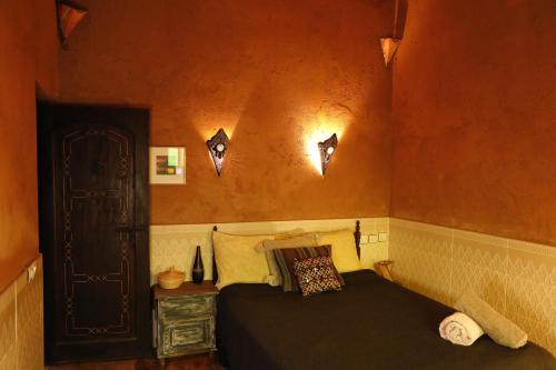 - une chambre avec un lit et deux lumières sur le mur dans l'établissement DAR OUZOUD Vegan, à Ouzoud