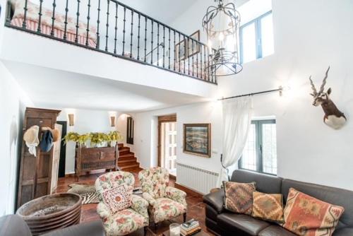 a living room with a couch and chairs and a staircase at Casa Rural Finca El Tobar in Ossa de Montiel