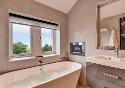 baño con bañera, lavabo y ventana en Feathered Nest en Hornby