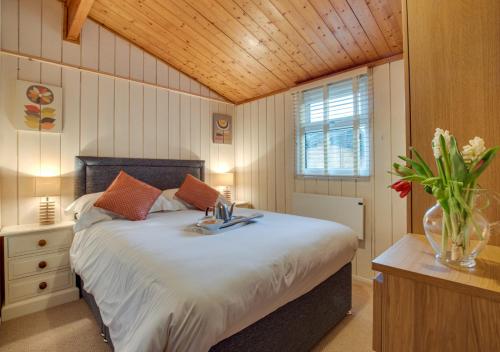 ein Schlafzimmer mit einem großen Bett und einer Vase aus Blumen in der Unterkunft Birch Lodge in Thornton Watlass