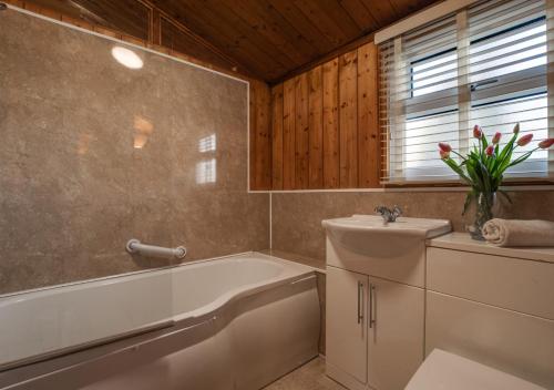 ein Badezimmer mit einer Badewanne, einem WC und einem Waschbecken in der Unterkunft Birch Lodge in Thornton Watlass