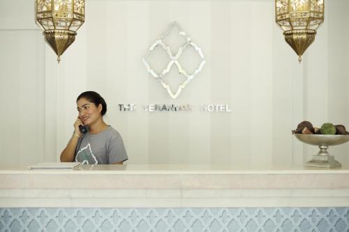 a woman sitting at a counter talking on a cell phone at The Verandah - SHA Extra Plus in Ao Nang Beach