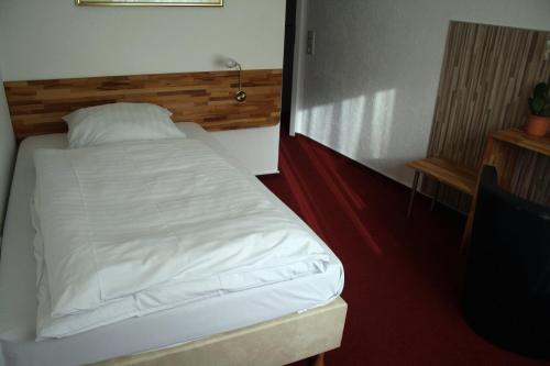 a bedroom with a white bed with a wooden headboard at Hotel-Nachtwächter in Unna