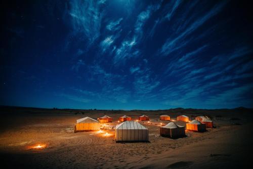a group of tents in the desert at night at Shooting Stars Camp in Merzouga