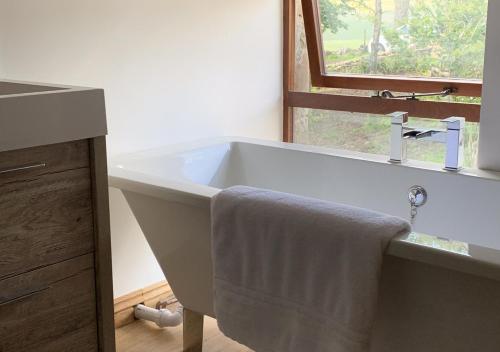 ein Badezimmer mit einem Waschbecken und einer Badewanne mit einem Handtuch in der Unterkunft Red Squirrel Cottage in Hawes