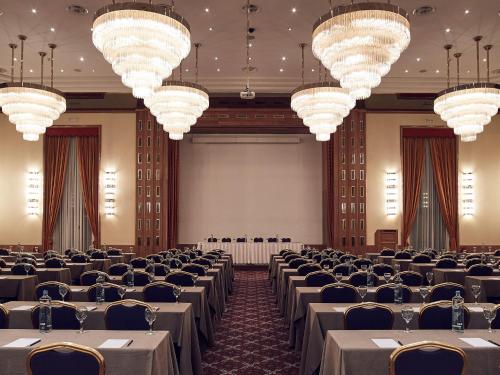 a banquet hall with tables and chairs and chandeliers at Hotel Du Lac Congress Center & Spa in Ioannina