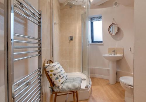 a bathroom with a shower and a chair and a sink at The Old Windmill in Kirkbymoorside