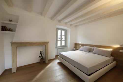 a white bedroom with a bed and a fireplace at Palazzo Riccamboni in Riva del Garda