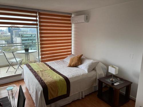 1 dormitorio con cama, mesa y balcón en Apart hotel Fraga, en Santiago