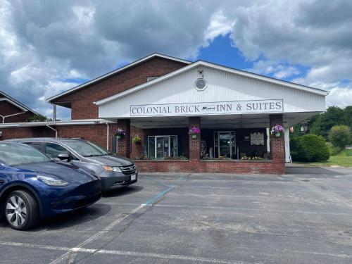 a building with cars parked in a parking lot at Colonial Brick Inn & Suites in Susquehanna