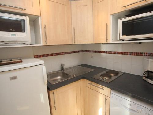 La cuisine est équipée de placards en bois, d'un évier et d'un four micro-ondes. dans l'établissement Studio fonctionnel proche des pistes avec coin chambre séparé, internet et cuisine équipée - FR-1-416-72, à La Toussuire