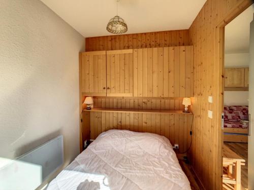 une chambre avec un lit dans une pièce aux murs en bois dans l'établissement Bel appart 2P cosy 4 pers, balcon, au cœur de La Toussuire - FR-1-416-144, à La Toussuire