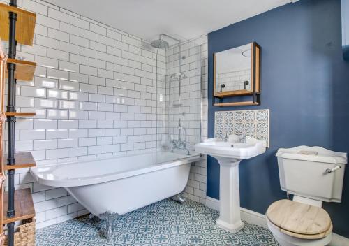a bathroom with a tub and a toilet and a sink at Pebble Beach Cottage in Rottingdean