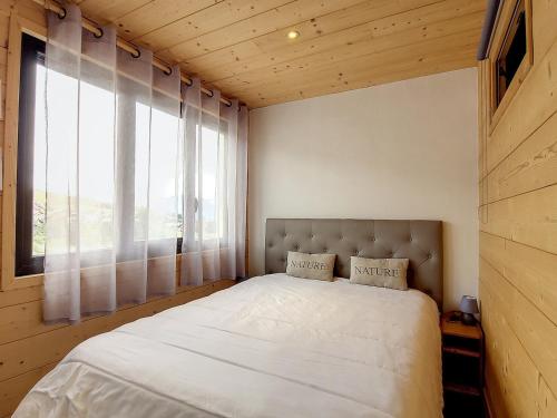 une chambre avec un lit avec une grande fenêtre dans l'établissement Appartement rénové 2 chambres, balcon sud, à 50m des pistes et commerces - La Toussuire - FR-1-416-145, à La Toussuire