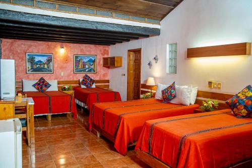 Habitación con 2 camas con sábanas rojas y mesa. en Hotel Panchoy by AHS, en Antigua Guatemala