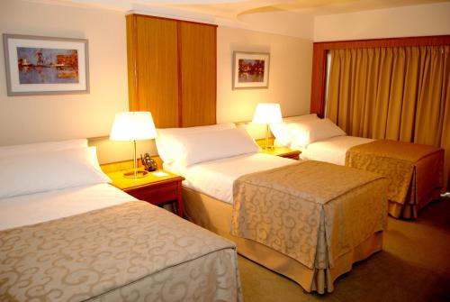 a hotel room with two beds and two lamps at Hotel Conte in Buenos Aires