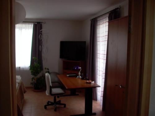 a room with a table and a chair and a television at Gästezimmer Ferienwohnung VILLA ALEXA, mit Wallbox in Woltersdorf